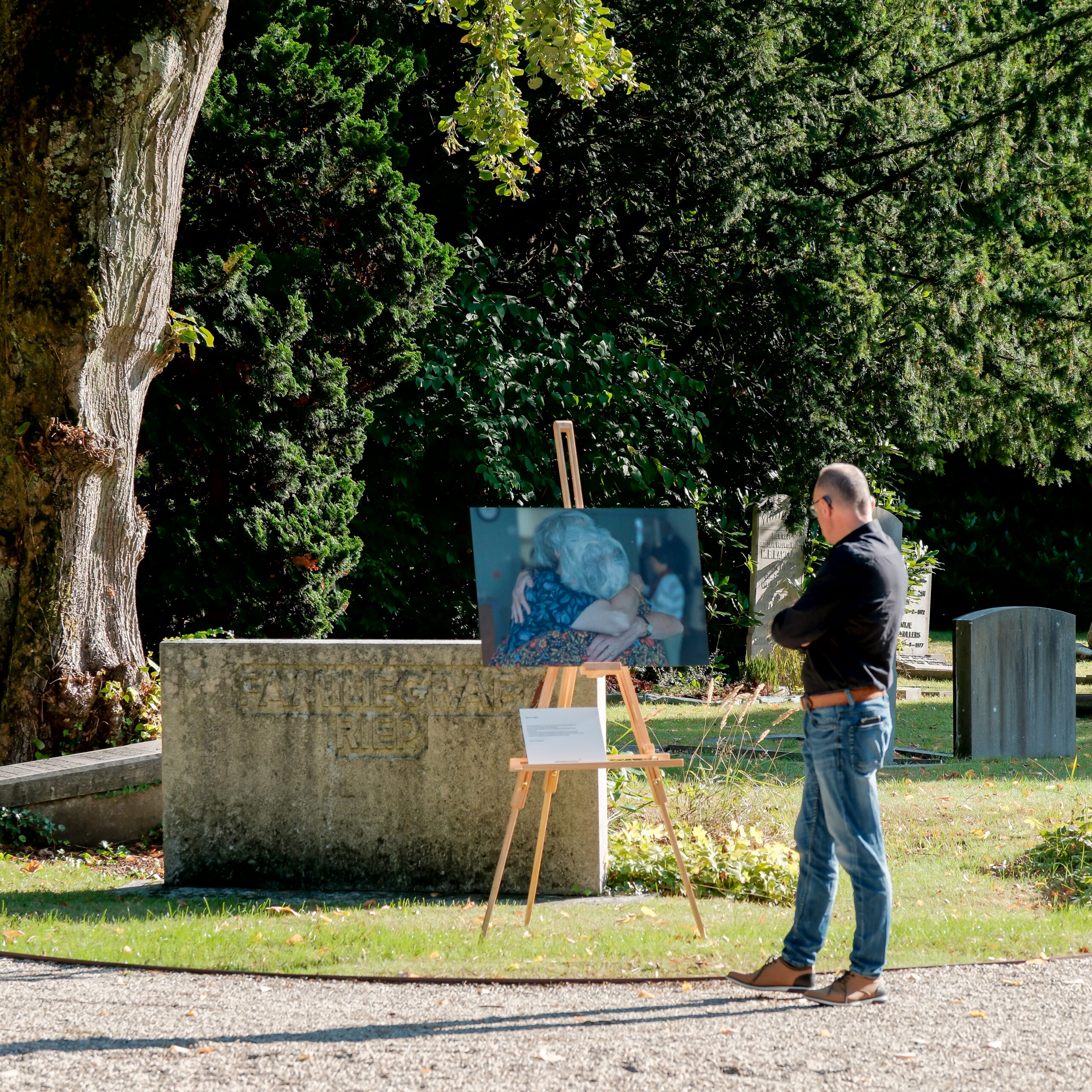 William bekijkt een grote print van een afscheid buiten tijdens een expositie